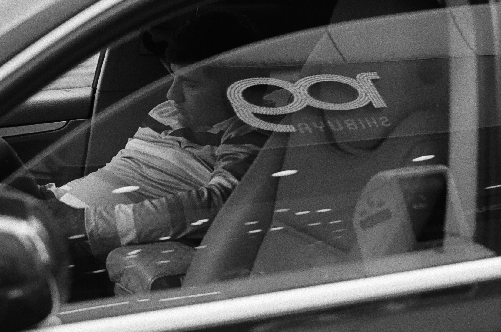 車窓越しに見える運転席の人と街の反射
