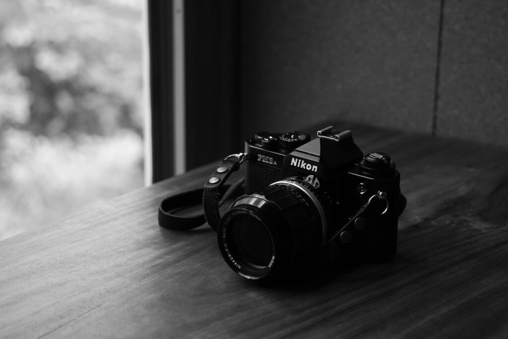 Nikon FM3A on a wooden table beside a window, in black and white