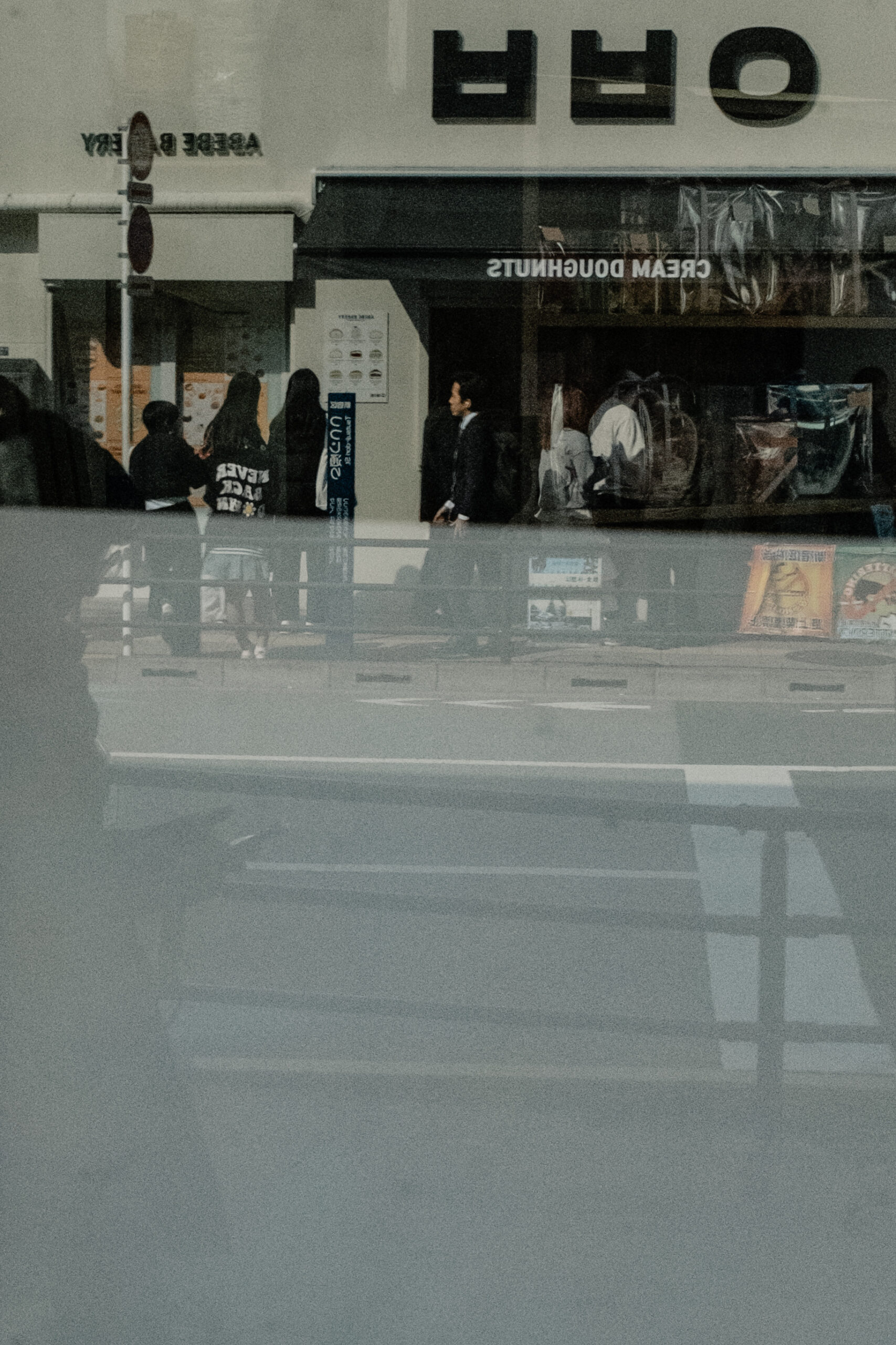 新大久保の店先を歩く人々とガラスに重なる街の反射